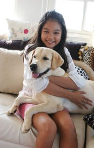 Happy Asian girl on animal print sofa with her pet dog